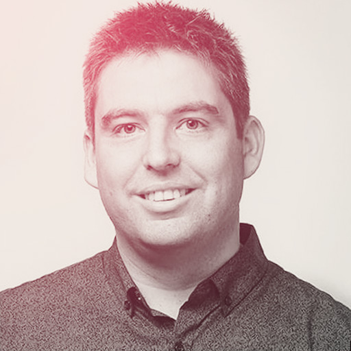 Aaron's portrait. A smiling Caucasian man with neat short hair. He's wearing a dark coloured top.